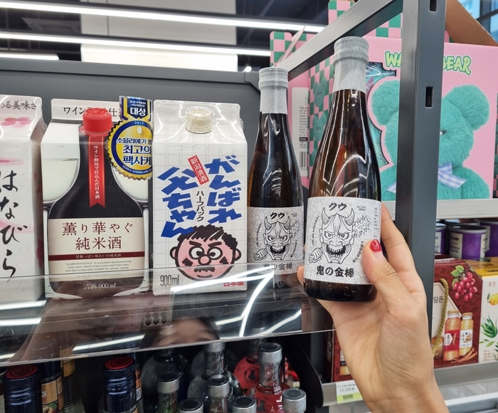 CU 매장 주류 매대에서 오니노카나보 사케 병을 집는 모습