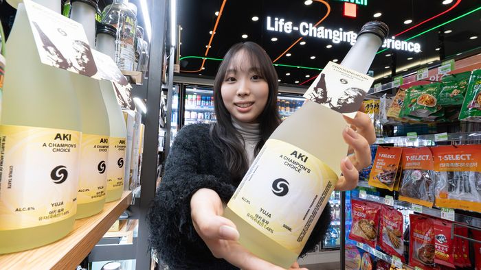 세븐일레븐 매장에서 아키유자 사케 병을 들어 보이는 모습